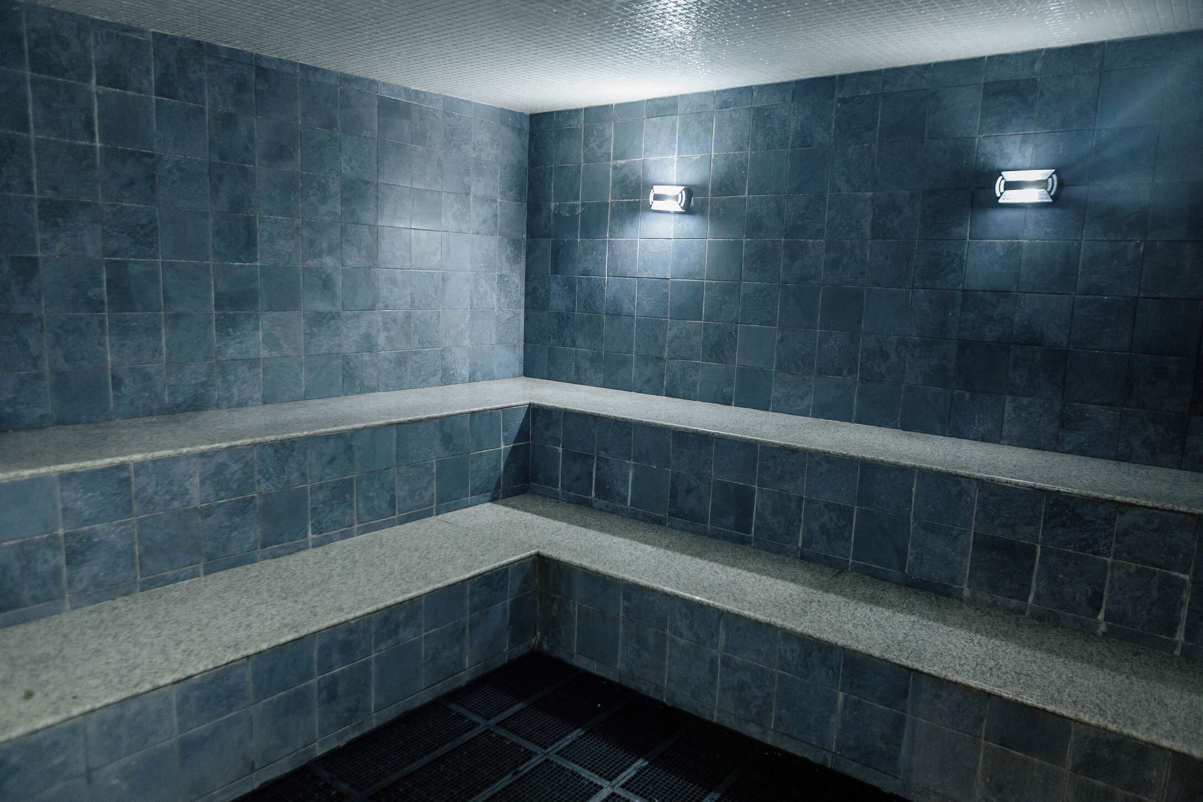 A tiled bathroom with a bench and a shower area.