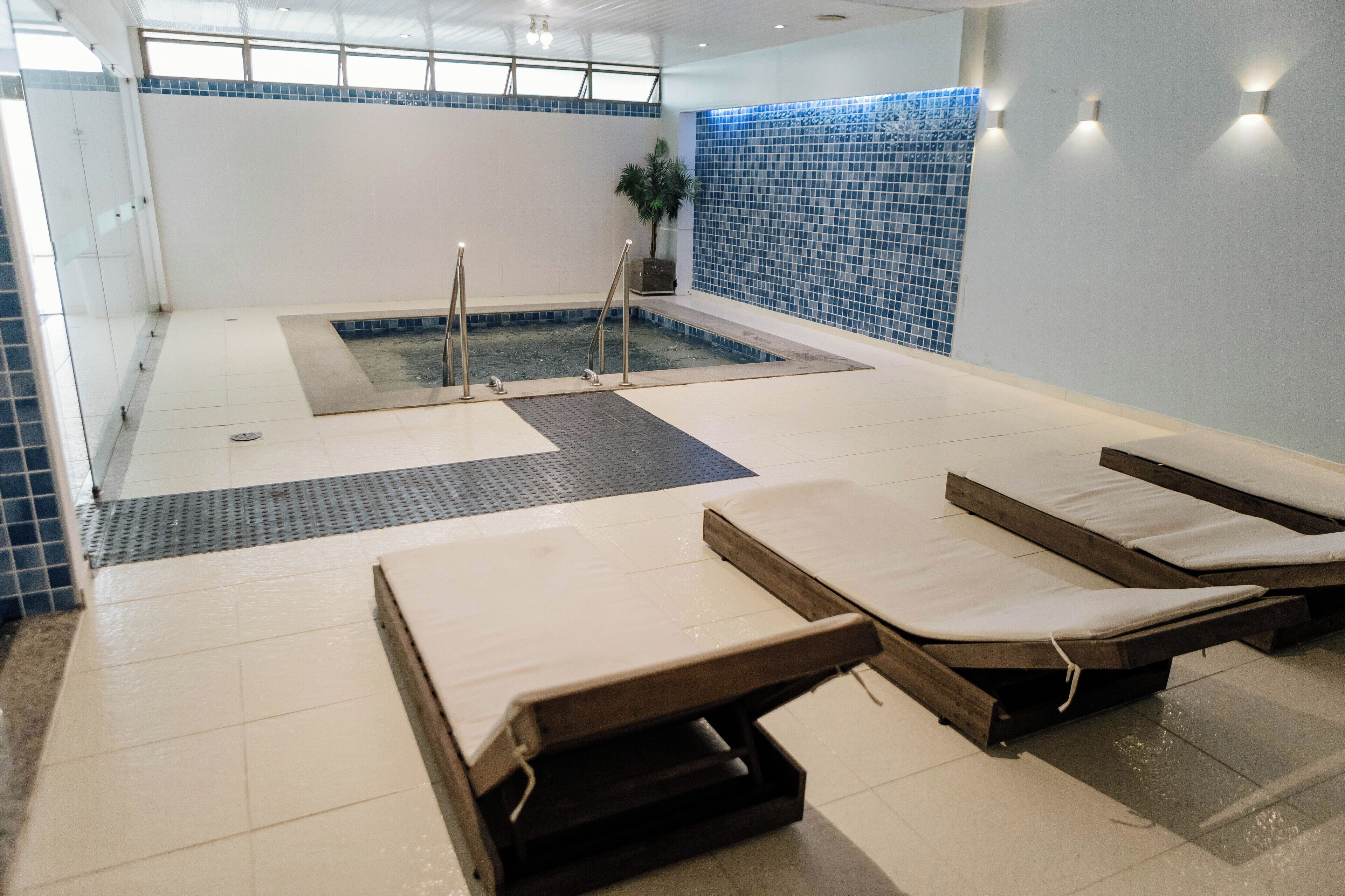 A spa area with a hot tub, lounge chairs, and a tiled wall.
