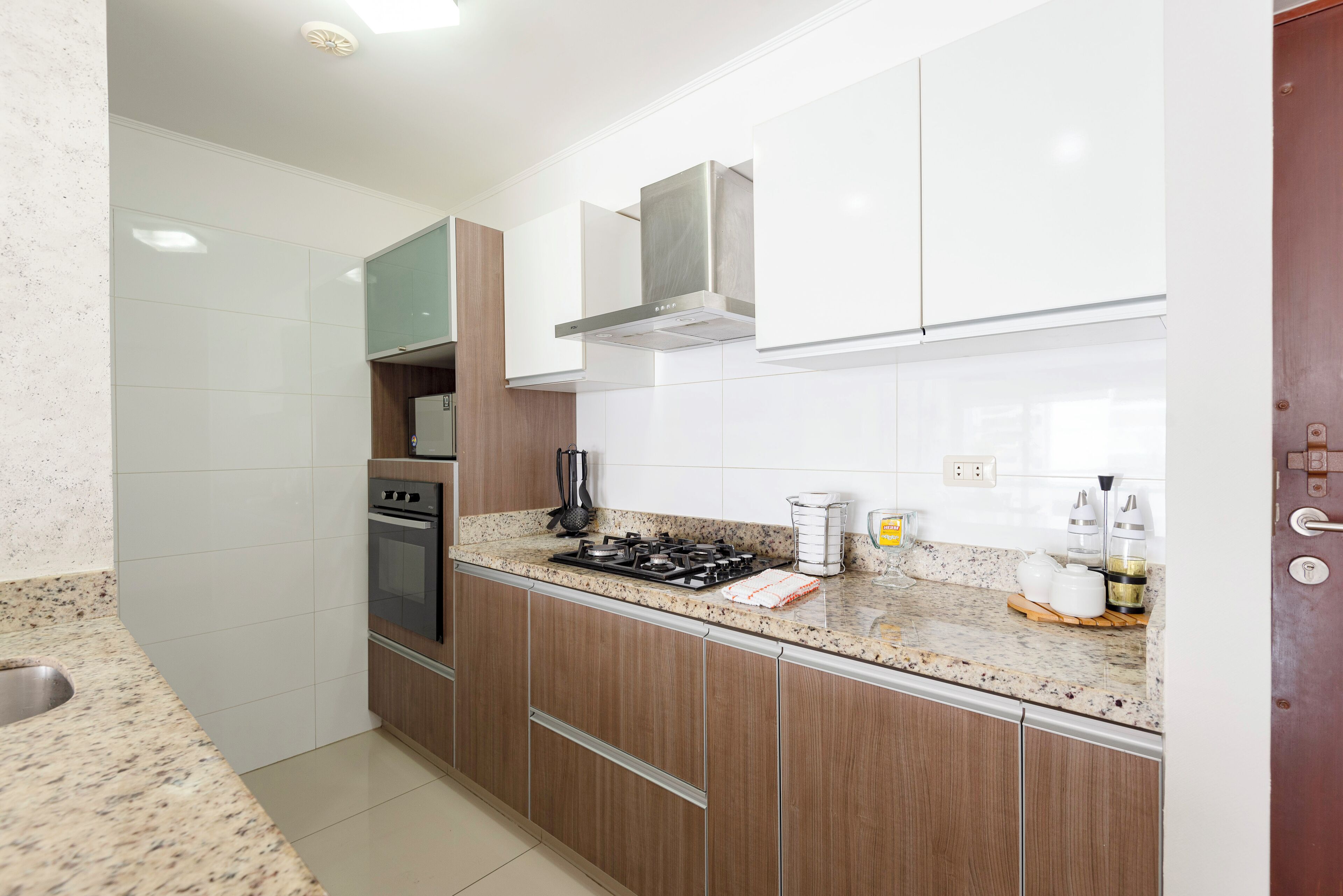 A modern kitchen with stainless steel appliances, wooden cabinets, and a granite countertop.