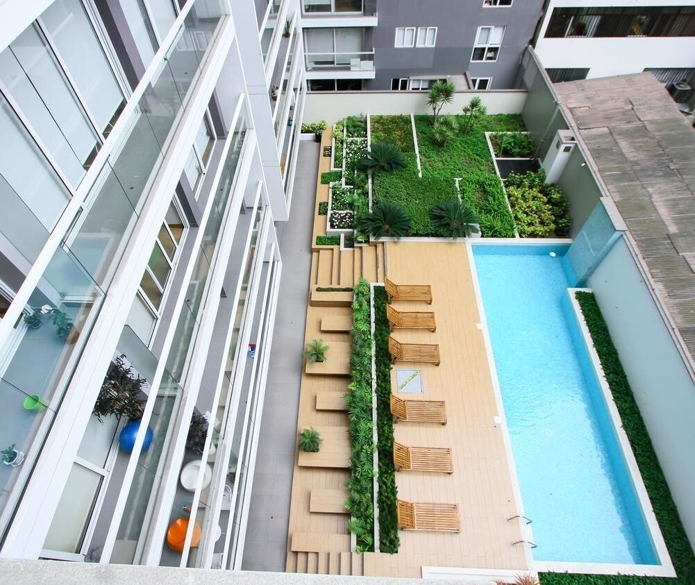 A rooftop pool with wooden loungers and a small garden area.
