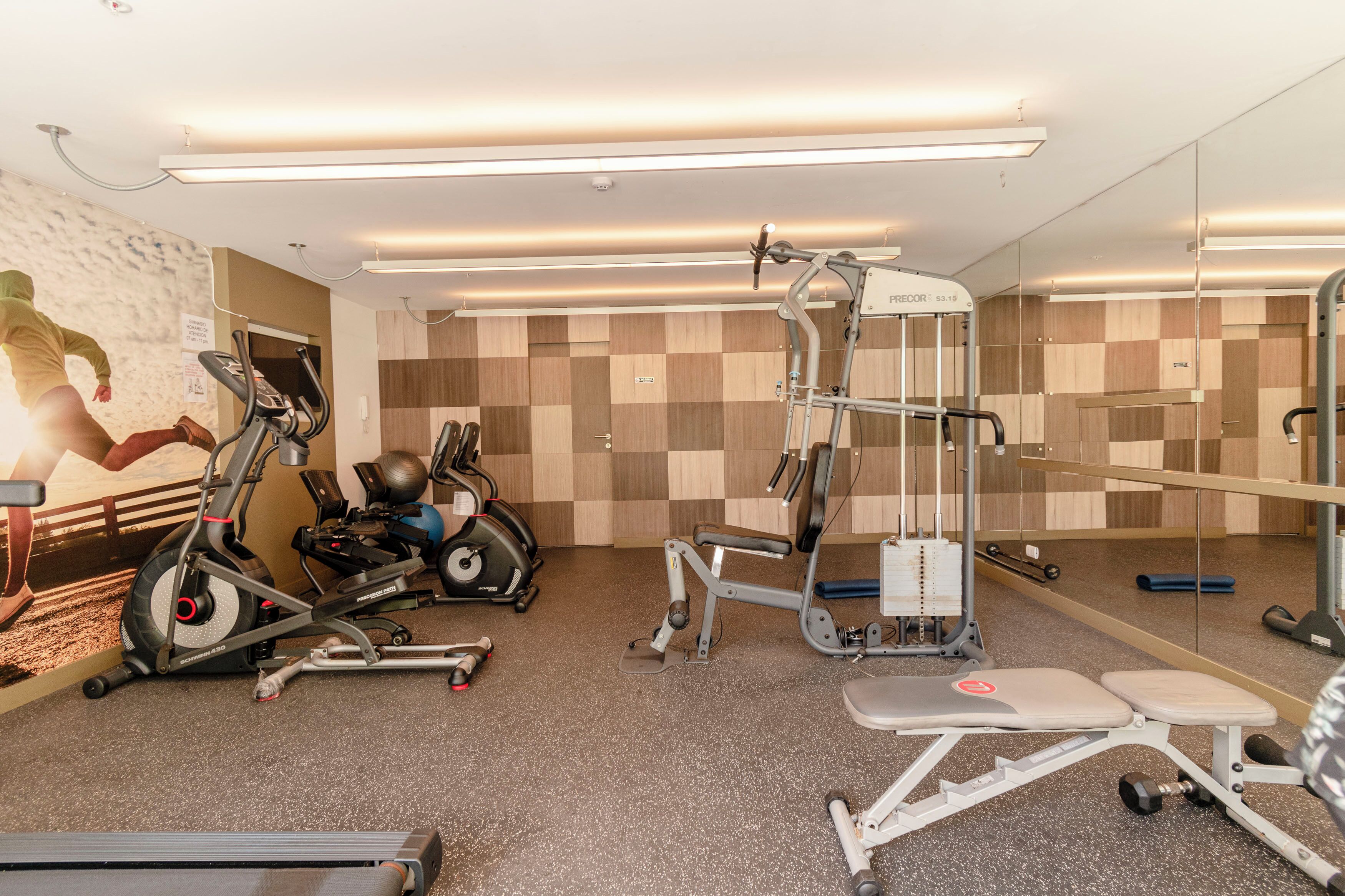 Ein Fitnessstudio mit Laufbändern, Crosstrainern und Gewichten.