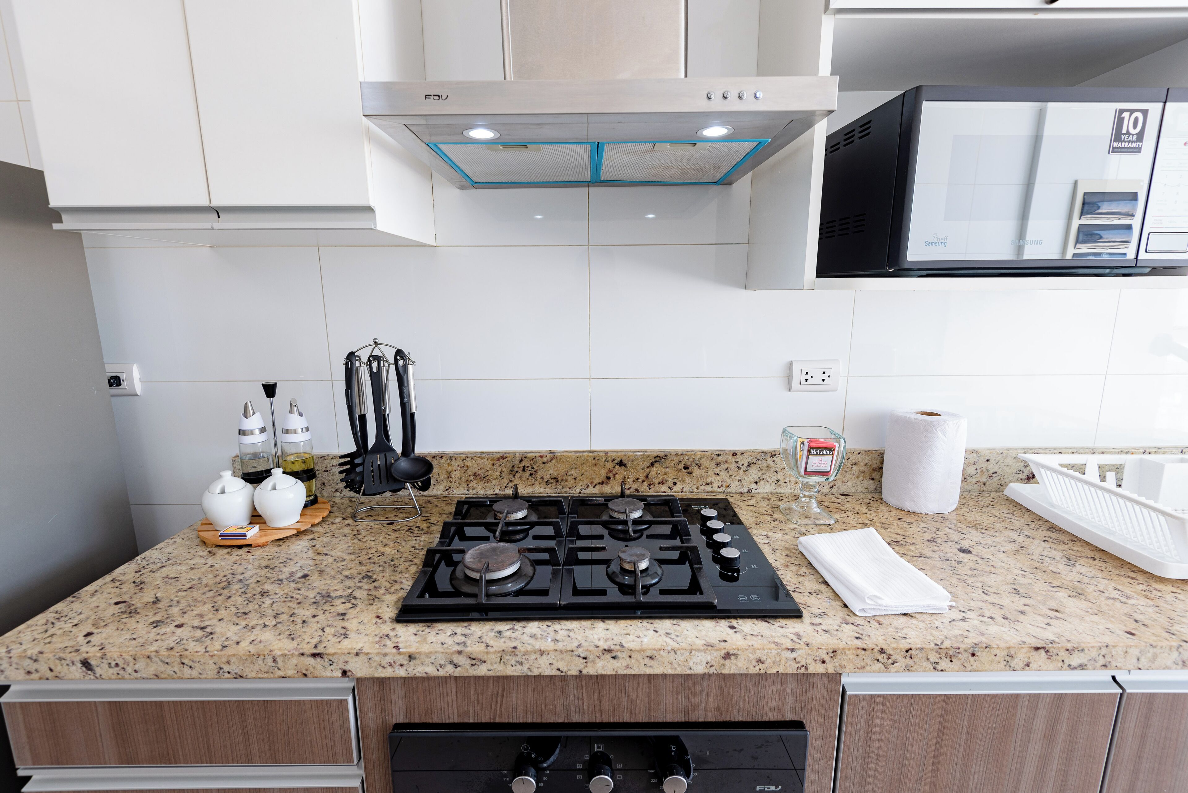 Une cuisine dotée d’un plan de travail en granit, d’une cuisinière à gaz et de meubles blancs.