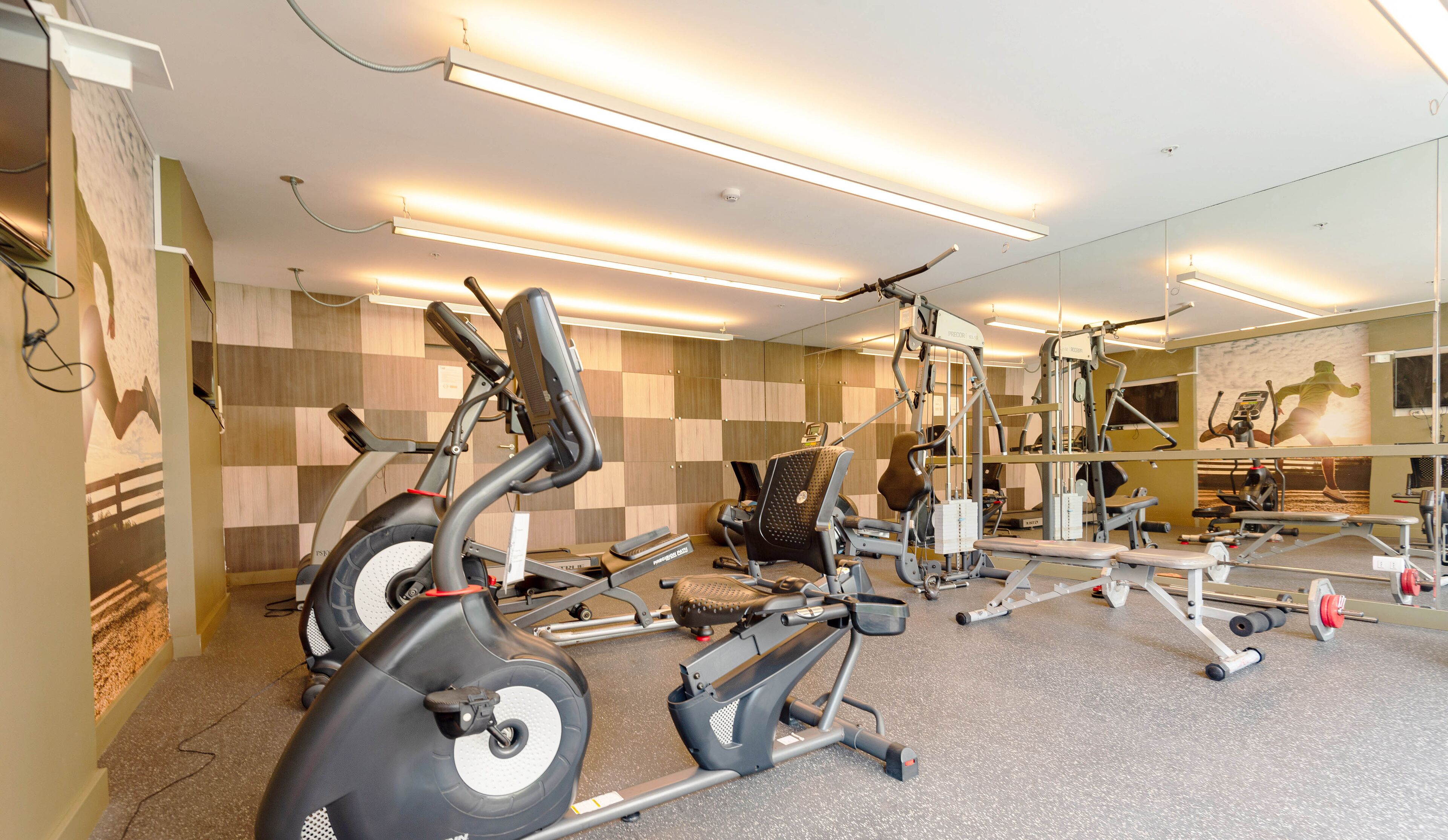 A gym with stationary bikes, a rowing machine, and weightlifting equipment.