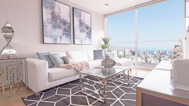 Un salon moderne avec un canapé blanc, une table basse en verre et une vue sur la ville grâce à de grandes fenêtres.
