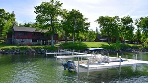 A lakeside property with a dock, a red house, and a stone building. - Trappers Landing Lodge (Walker)