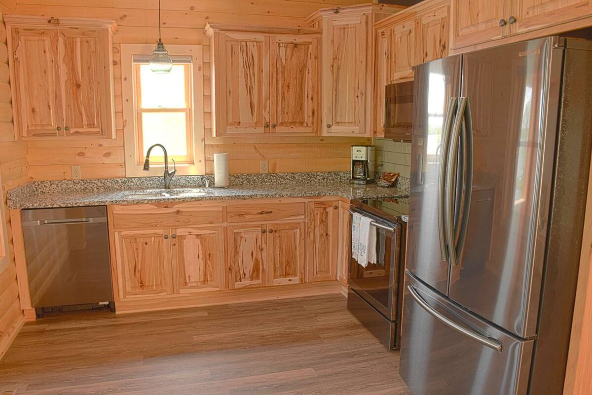 A kitchen with wooden cabinets, a stainless steel refrigerator, a dishwasher, and a coffee maker.