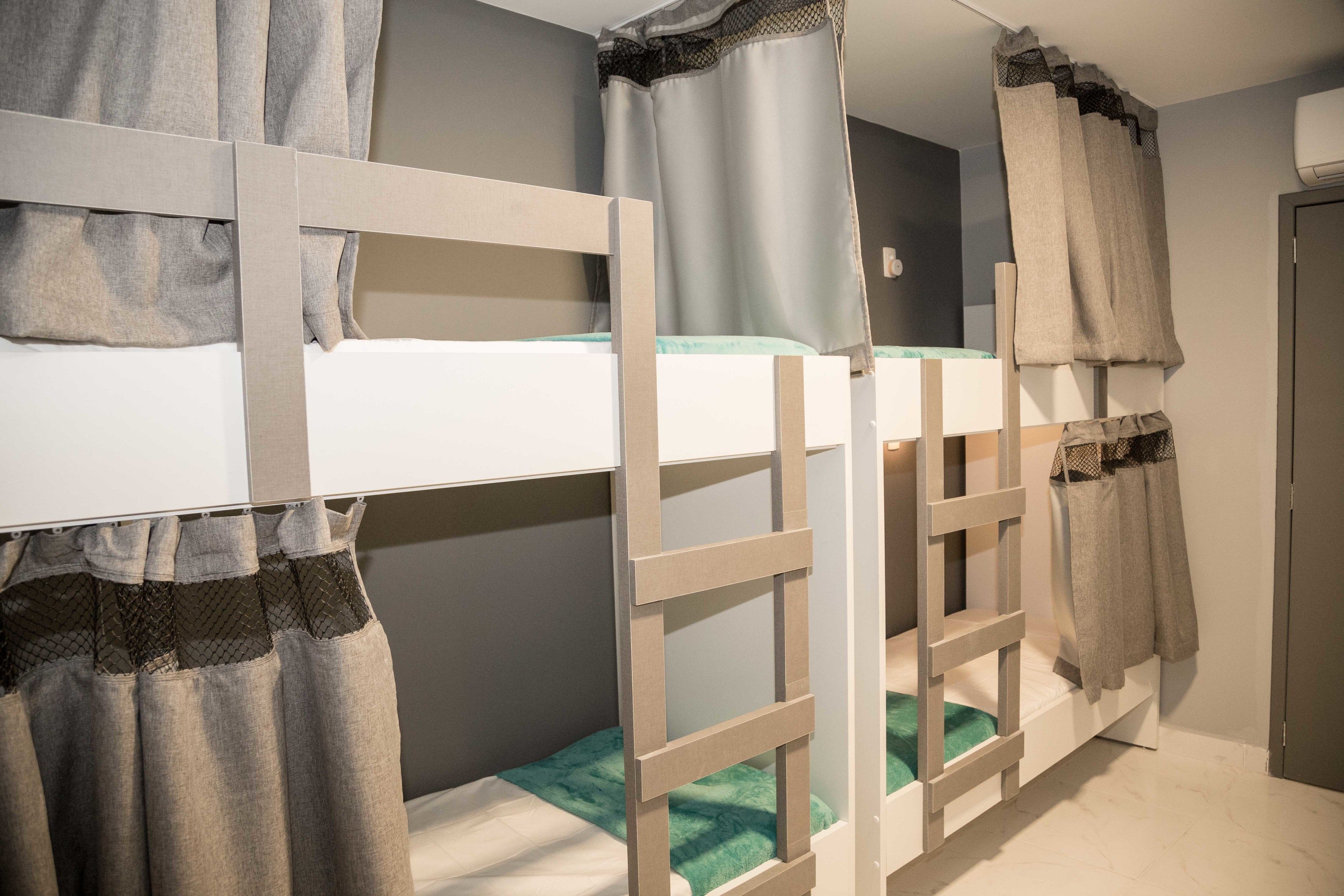 A bunk bed with a ladder, grey curtains, and a white headboard.