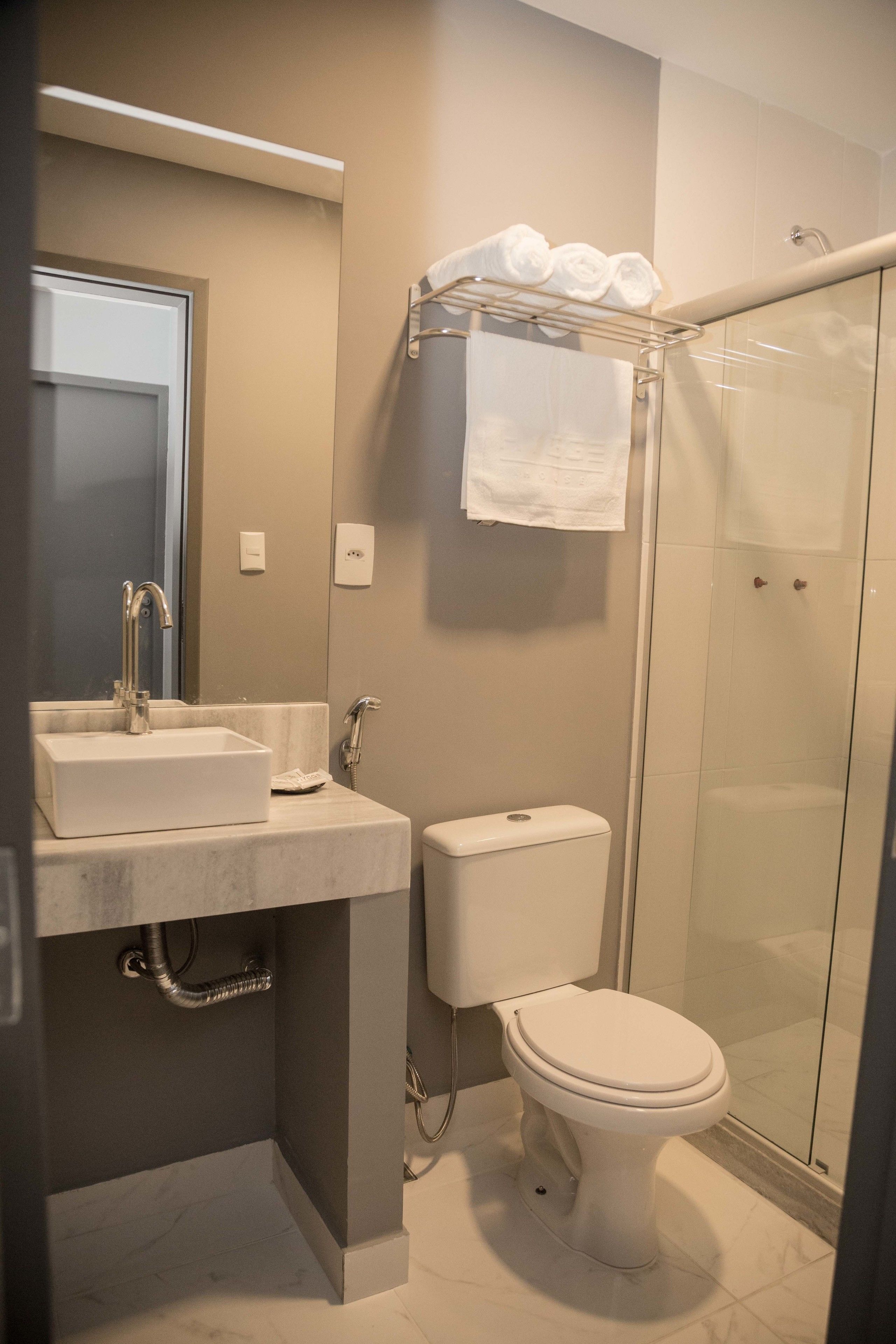 Een moderne badkamer met een wastafel, toilet en een douchecabine met glazen wanden.