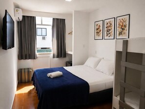 A hotel room with a bed, a TV, a window with curtains, and three framed pictures on the wall. - Ref House (Rio de Janeiro)
