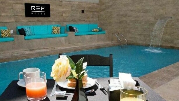 Desayuno junto a la piscina, con una mesa, platos de comida y un vaso de jugo de naranja.