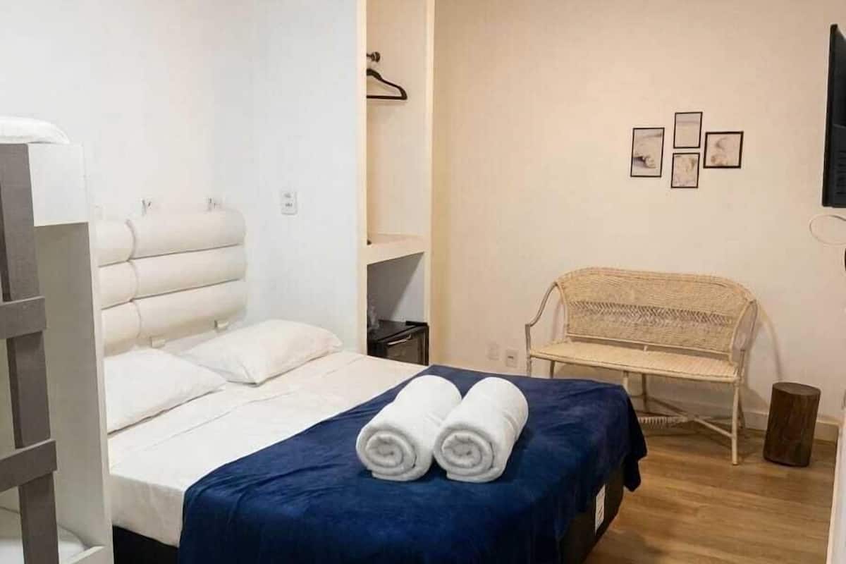 Une chambre à coucher avec un lit, une chaise, une petite table et un téléviseur fixé au mur.