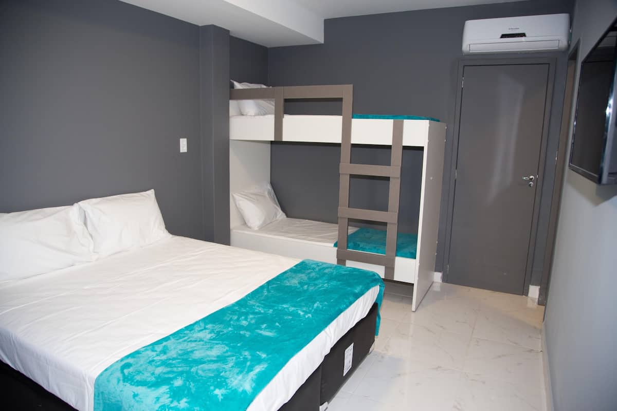 Une chambre avec un lit superposé, un lit simple, une armoire et un climatiseur fixé au plafond.