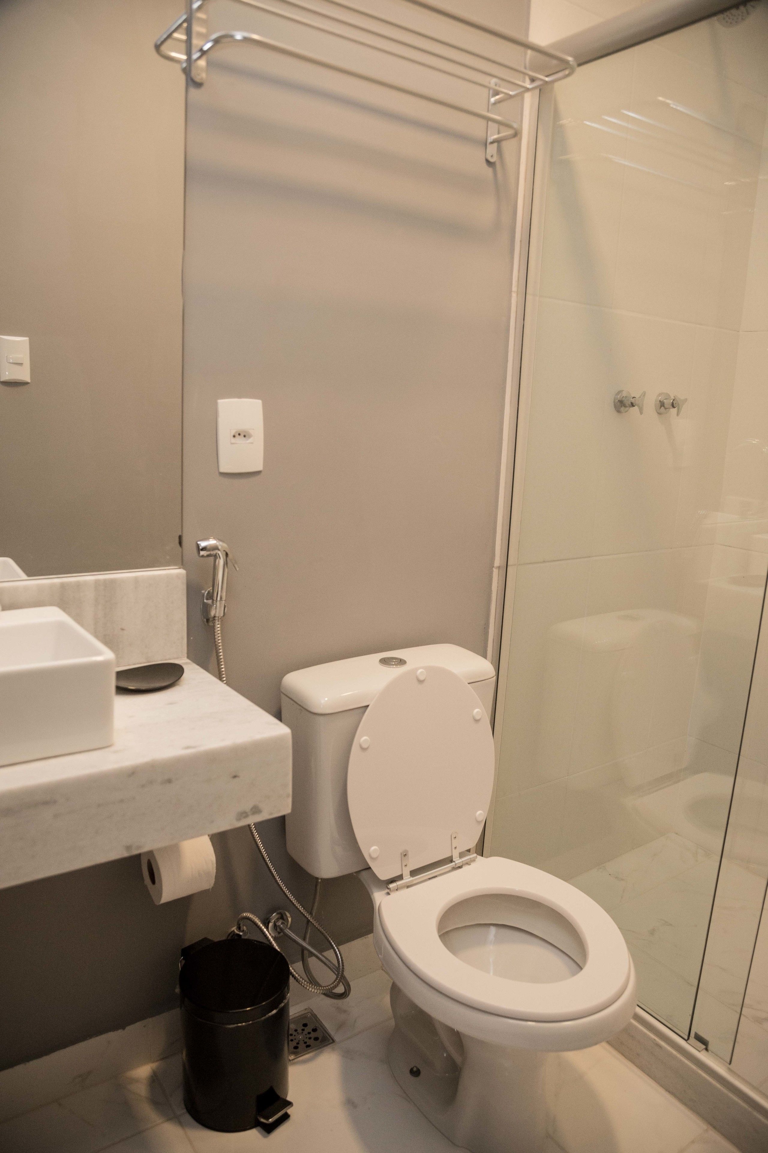 A modern bathroom with a toilet, a shower enclosure, and a sink with a mirror.