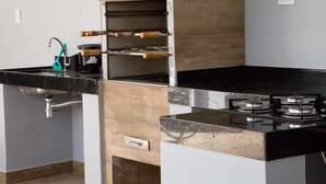 Una cocina con encimera negra, electrodomésticos de acero inoxidable y armarios de madera.