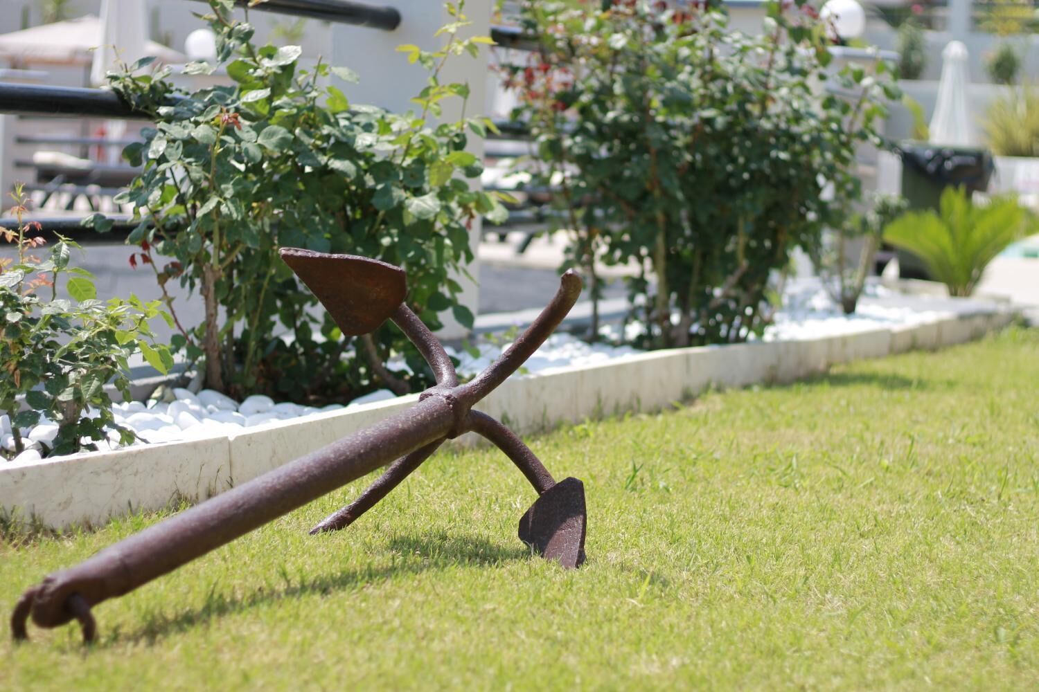 A garden with a metal sculpture, white gravel border, and green plants.