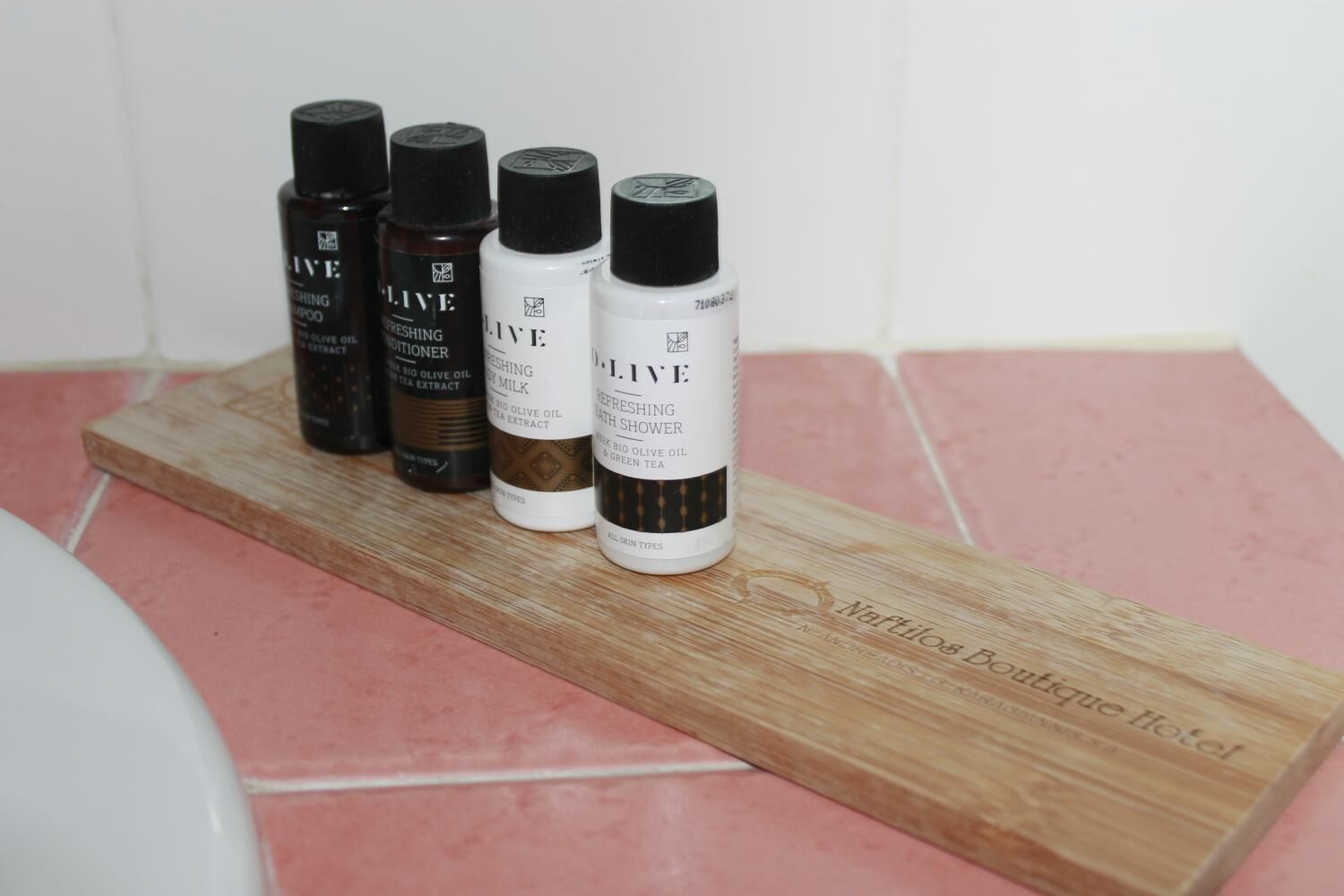 Cuatro botellas de productos D. L.IVE sobre una bandeja de madera en un baño.
