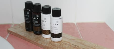 Cuatro botellas de productos D. L.IVE sobre una bandeja de madera en un baño.