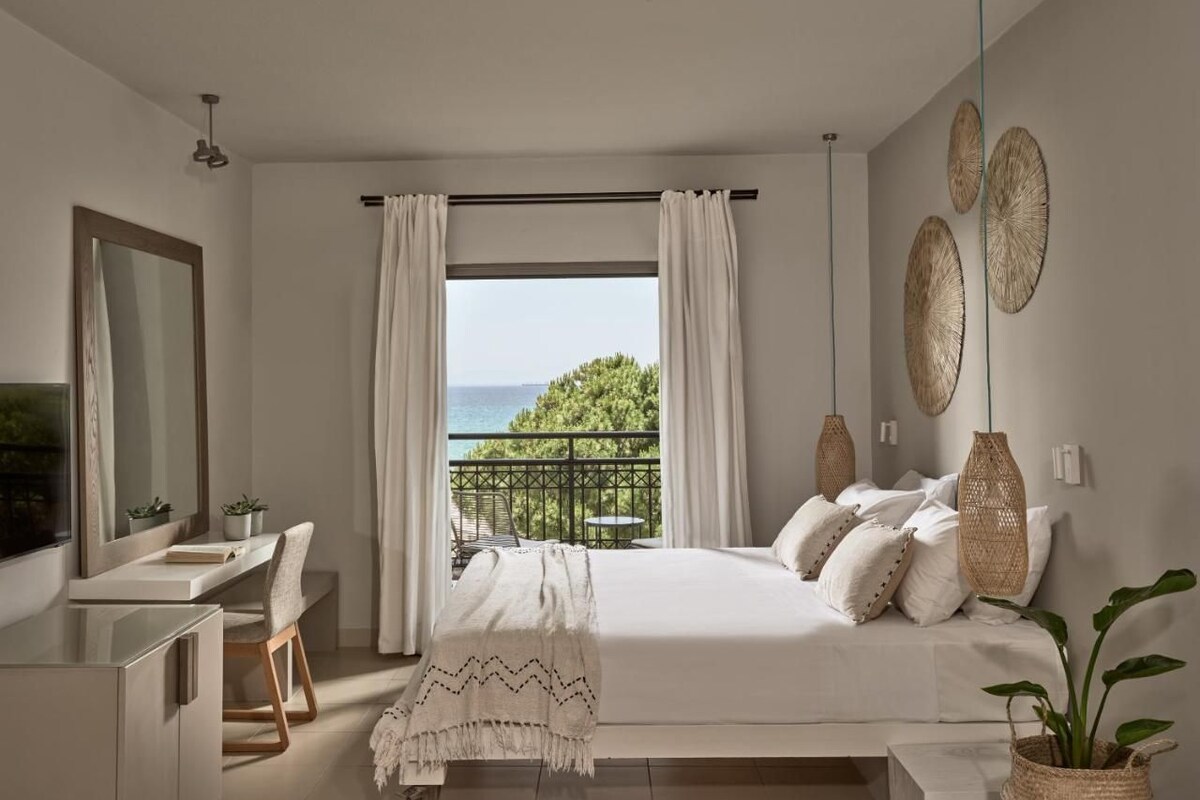 Une chambre à coucher avec un lit, une table de chevet et une vue sur la mer.