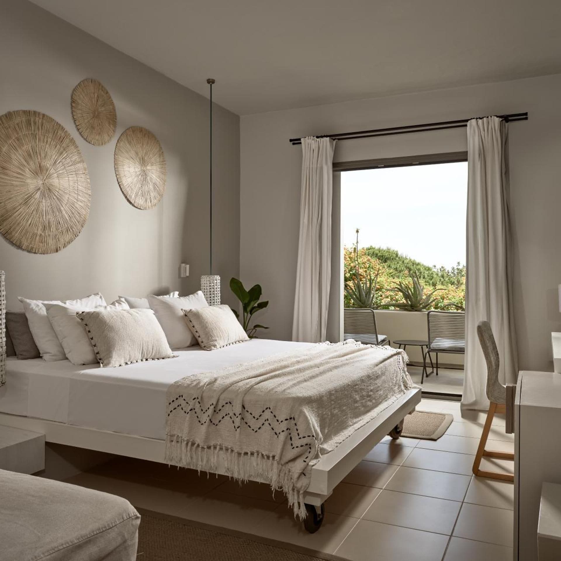 Un dormitorio moderno con una cama grande, vistas a zonas verdes y decoración en la pared.