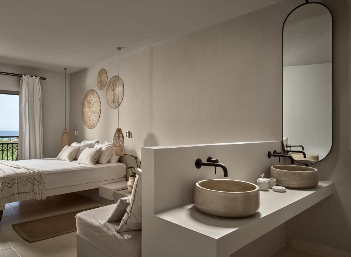 Un dormitorio moderno con una cama grande, un tocador empotrado con un lavabo redondo y un espejo grande.