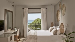 A bedroom with a bed, bedside table, and a view of the sea.