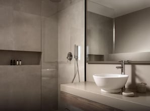 A modern bathroom with a large mirror, a white sink, and a shower area.