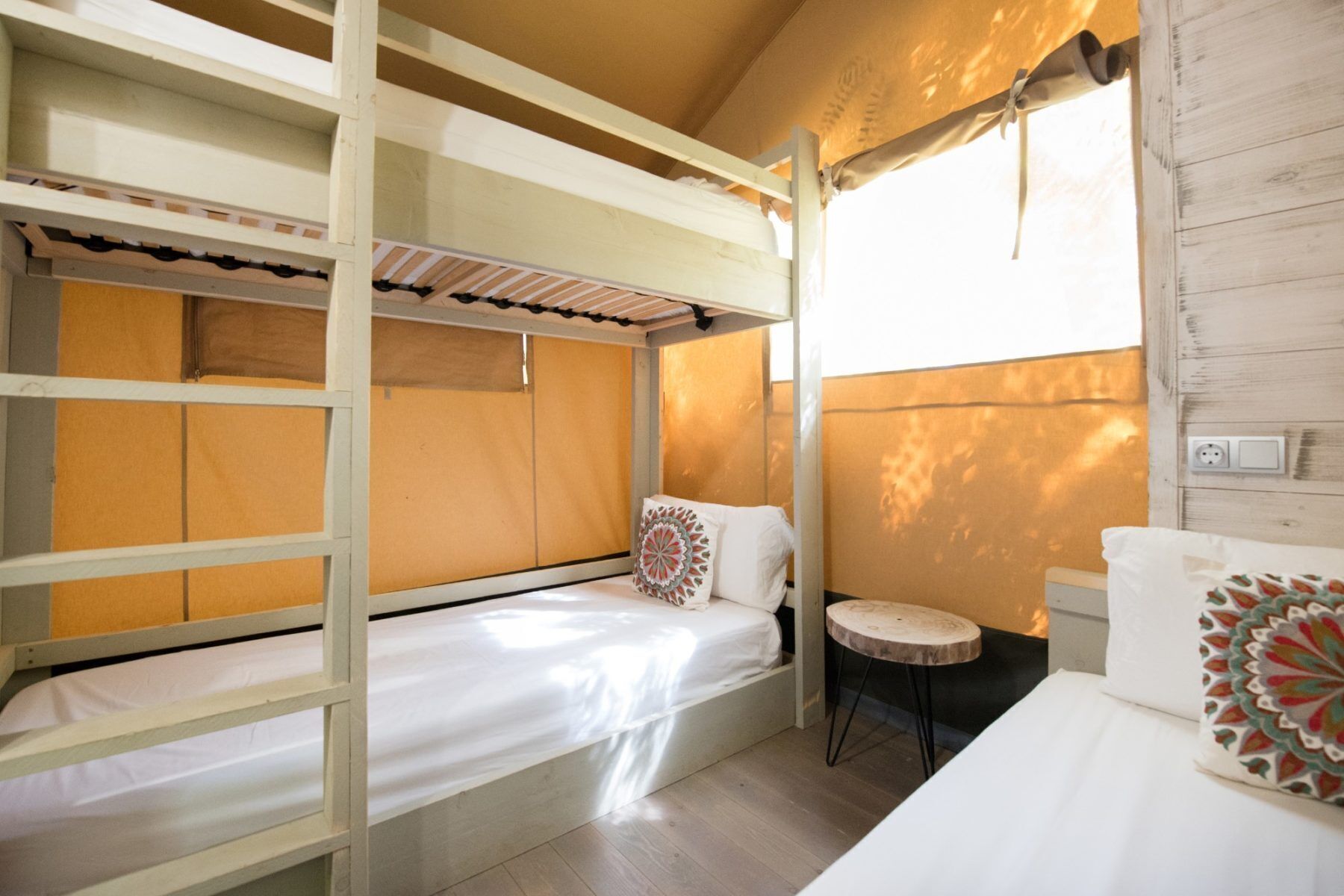 A bunk bed room with a small round table and a window.