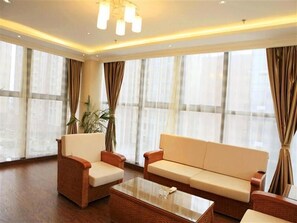 A spacious living area with a sofa and chairs, a coffee table, and large windows with curtains. - GreenTree Inn Changzhou Zhongwu Avenue Lihua  Hotel (Changzhou)
