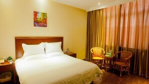 A hotel room with a large bed, a nightstand, a chair, a window with curtains, and a painting on the wall. - GreenTree Inn Changzhou Zhongwu Avenue Lihua  Hotel (Changzhou)