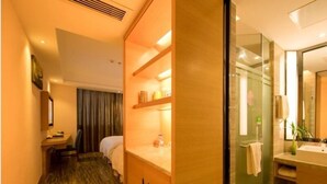 A hotel room with a bed, a desk, a small table, a mirror, and a bathroom with a sink and mirror. - GreenTree Eastern Bijie Qixingguan Zhaoshanghuayuan Hotel (Bijie)