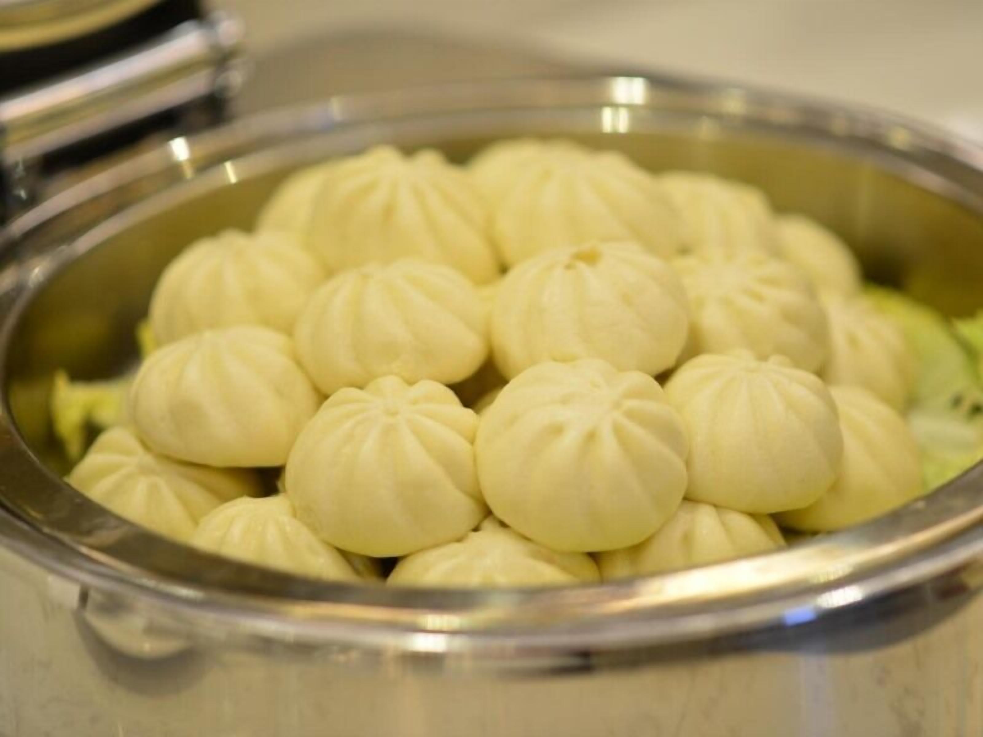 A stainless steel pot filled with white, round, steamed buns.