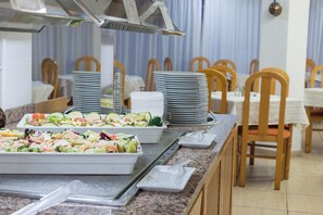 A buffet setup with various food items and stacked plates. - Aparthotel Alcudia Beach (Alcúdia)