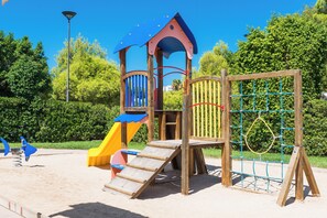 Un parque infantil con tobogán, red de escalada y estructuras de madera.