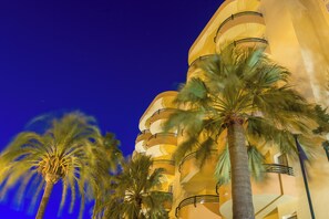 A building with a unique architectural design featuring curved balconies and palm trees in front. - Aparthotel Alcudia Beach (Alcúdia)