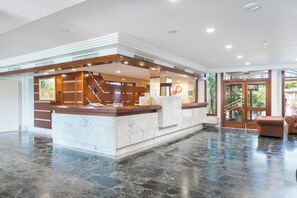 A reception area with a marble counter, wooden accents, and a glass door leading outside.