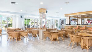 A spacious indoor area with wicker furniture and a central pillar, featuring a counter and seating area. - Aparthotel Alcudia Beach (Alcúdia)