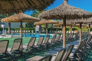 A poolside area with lounge chairs and thatched umbrellas. - Aparthotel Alcudia Beach (Alcúdia)