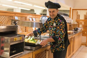 Une personne servant de la nourriture dans une cuisine équipée d’appareils en acier inoxydable et dotée de panneaux en bois.