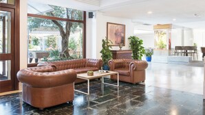 A spacious lobby with leather sofas, a coffee table, and potted plants. - Aparthotel Alcudia Beach (Alcúdia)