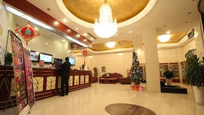 A hotel lobby with a reception desk, a chandelier, a Christmas tree, and a large mirror. - GreenTree Inn XuZhou PiZhou Xinsu Center Fuzhou Road Express Hotel (Xuzhou)