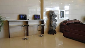 A reception area with a marble counter, two monitors, a statue, and a sofa. - GreenTree Inn XuZhou PiZhou Xinsu Center Fuzhou Road Express Hotel (Xuzhou)