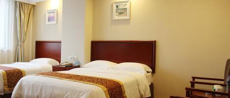 A hotel room with two beds, a wooden headboard, a chair, and a nightstand with a phone.