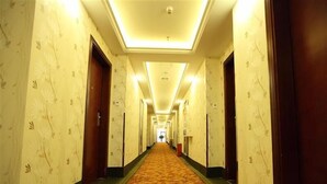 A hotel hallway with a carpeted floor, wooden doors, and patterned wallpaper. - GreenTree Business Inn HuiZhou South Railway Station DanShui RenMin Road Business Hotel (Huizhou)