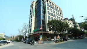 A multi-story hotel with a modern design, featuring a prominent entrance and a flagpole. - GreenTree Business Inn HuiZhou South Railway Station DanShui RenMin Road Business Hotel (Huizhou)