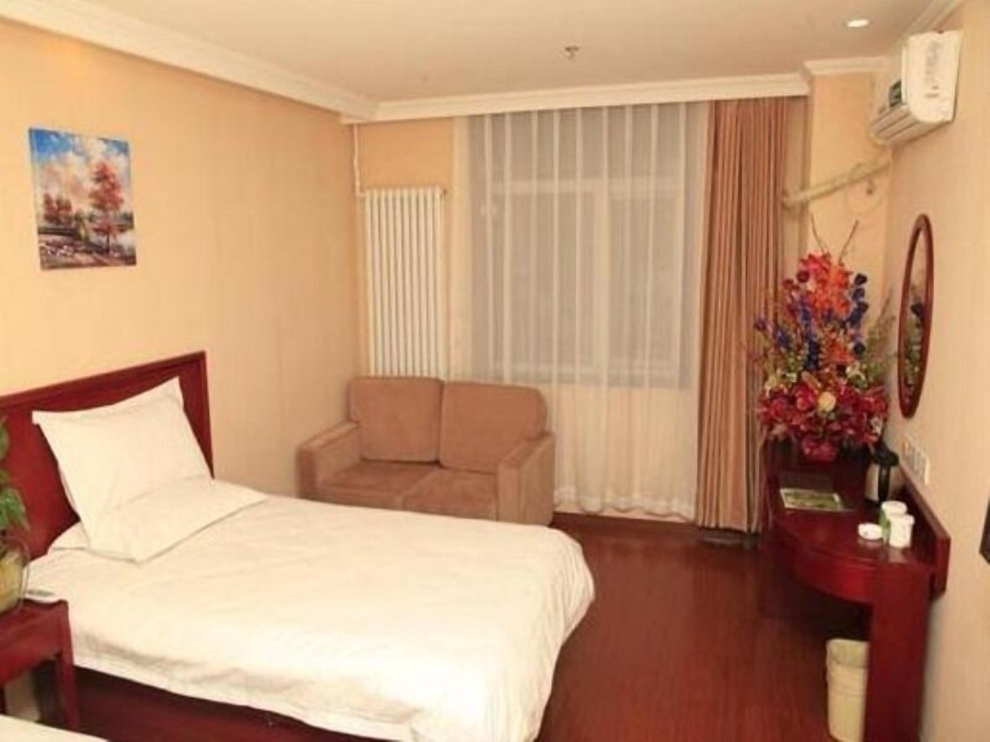 Ein Hotelzimmer mit einem Bett, einem Sessel, einem Schreibtisch mit Spiegel und einem Fenster mit Vorhängen.