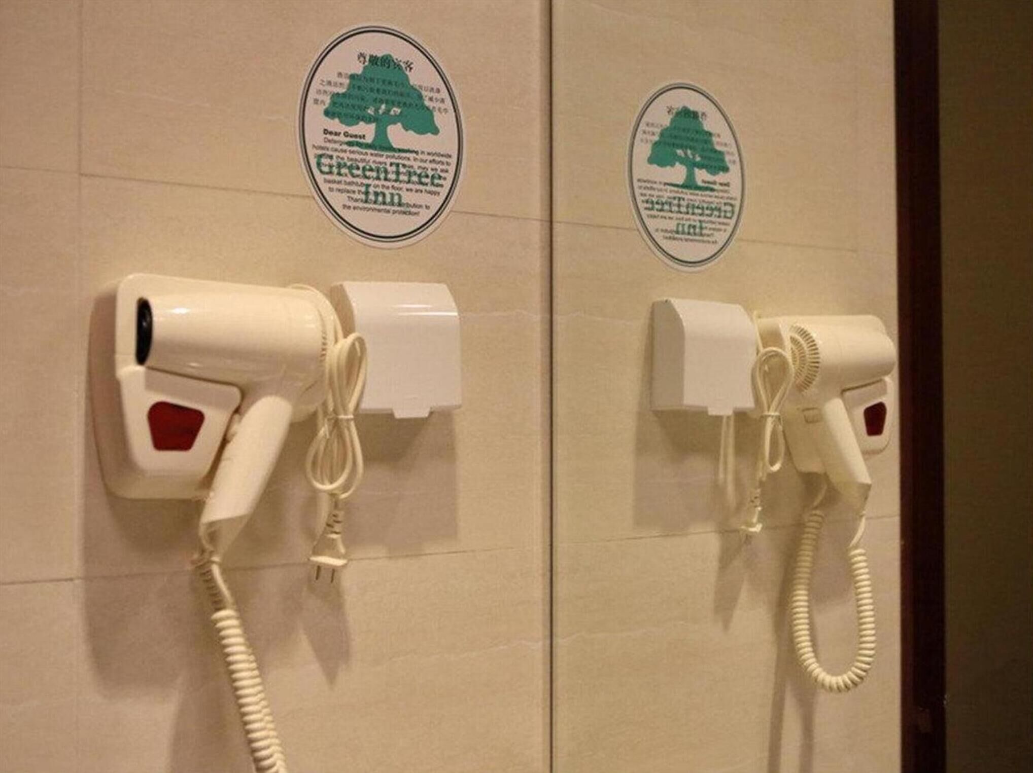 Deux sèche-cheveux fixés au mur, avec un autocollant représentant un arbre vert au-dessus de chacun.