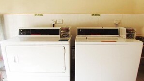 Two white washing machines side by side in a room with a tiled floor and a plain wall. - Greentree Inn Beijing Yanqing Gaota Rd Express Hotel (Yanqing)