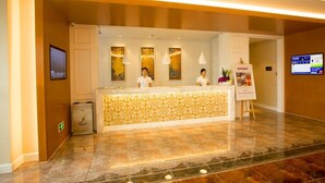 A hotel reception area with a marble floor, a reception desk, and a digital screen on the wall. - GreenTree Inn Yancheng Jianhu Oubaoliya Zunyuan Express Hotel (Yancheng)