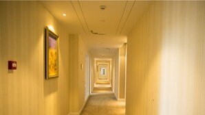 A hotel hallway with a carpeted floor, wooden paneling on the walls, and framed artwork. - GreenTree Inn Yancheng Jianhu Oubaoliya Zunyuan Express Hotel (Yancheng)