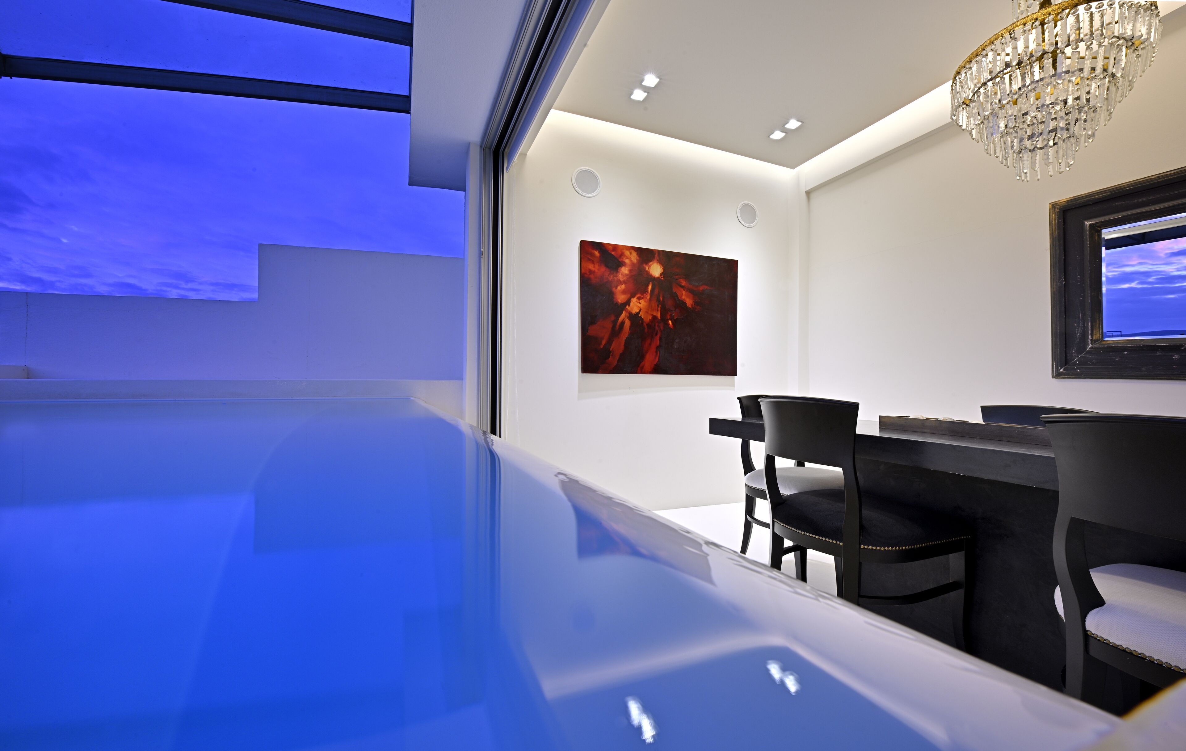 A modern interior with a pool, a dining area with chairs and a table, and a chandelier.